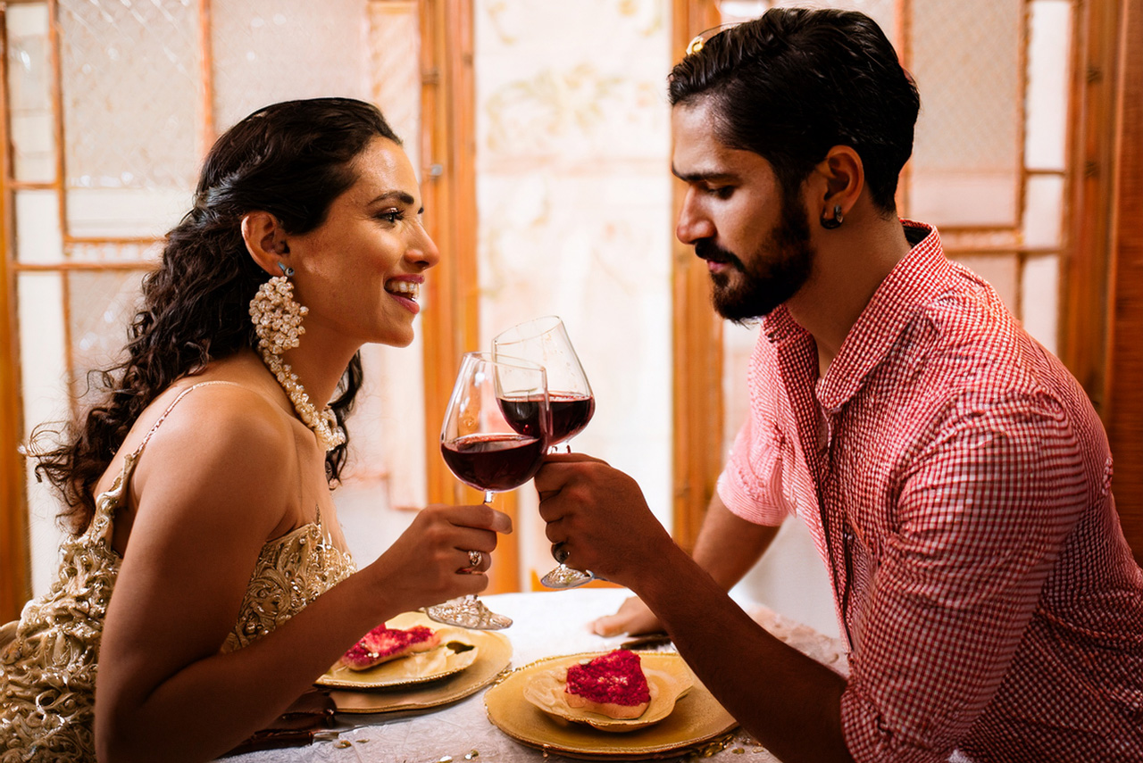 Couple clinking wine glasses on their anniversary, with a wine subscription gift box in the background.